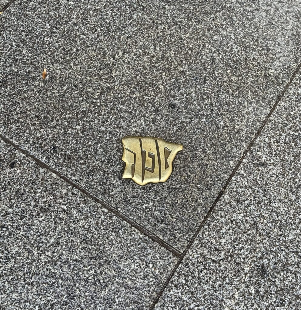 Bronze or Brass pavement marker with Hebrew letters on a granite surface in Segovia, Spain. Shows the word "Sefarad", the Hebrew name for the Iberian Peninsula.